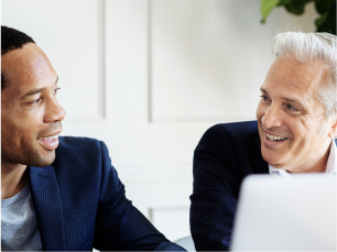 Image of two men talking in front of laptop