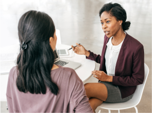 Image of two women sitting at desk and talking