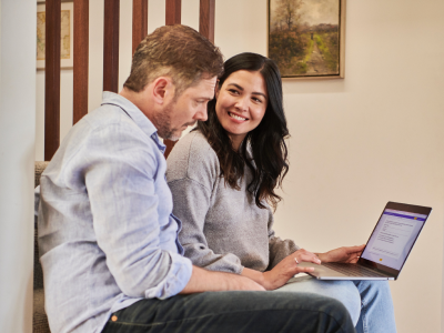 Man and woman sitting next to each other in house looking at laptop