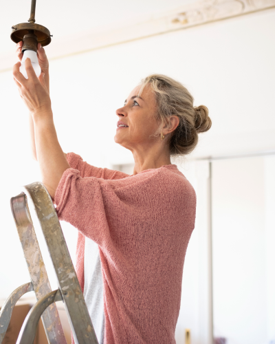Image of blond woman on changing out a lightbulb 