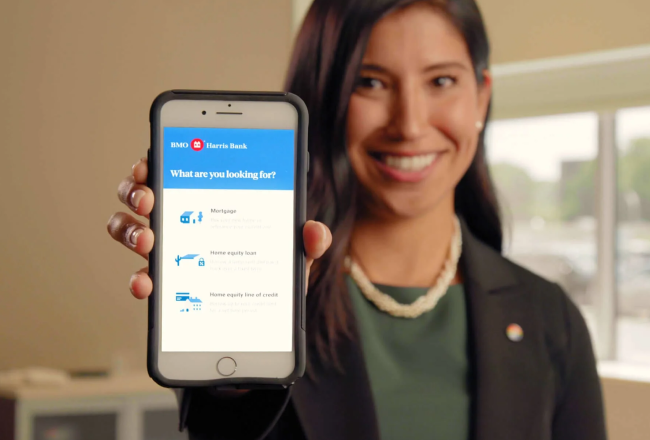 Image of woman holding up a mobile phone that reads "What are you looking for?" below a BMO Harris Bank Logo