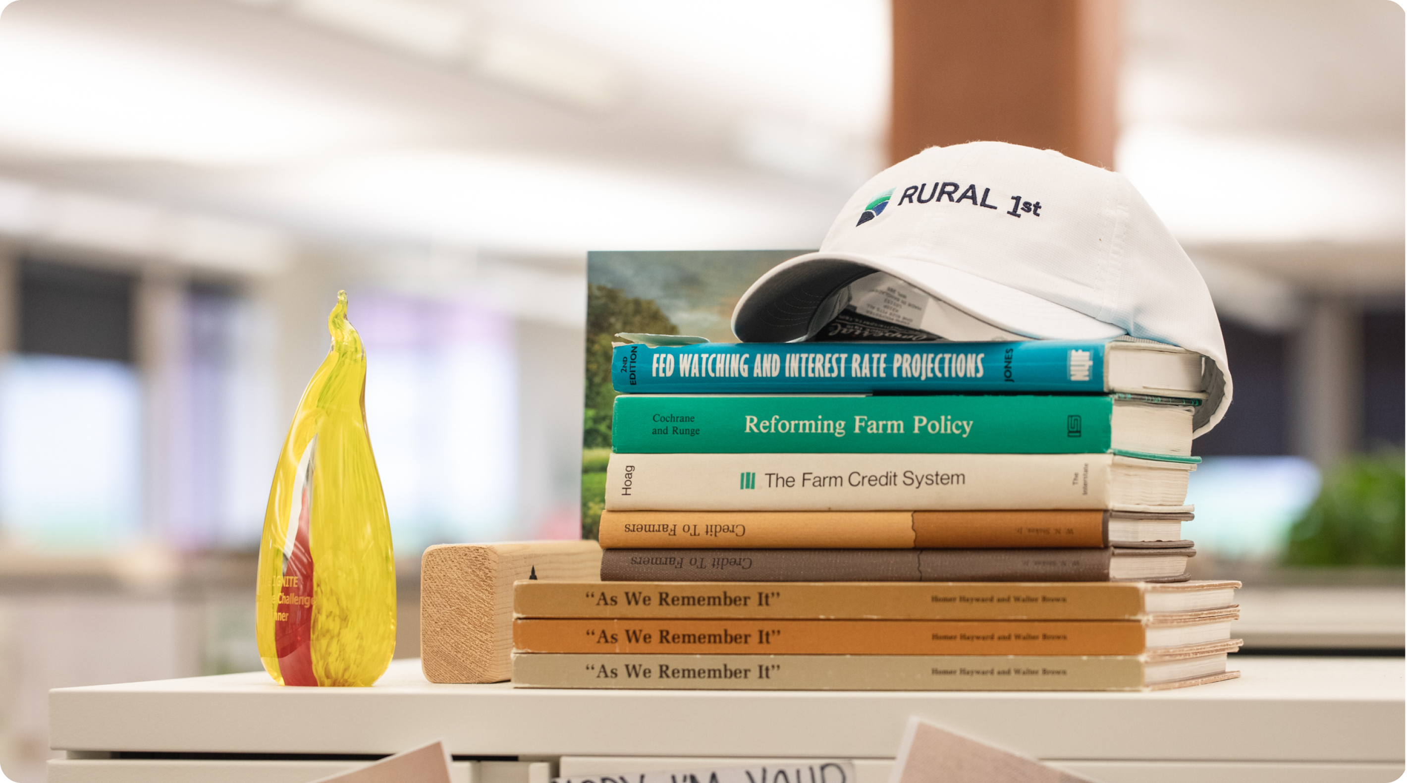 Image of stacked books with a Rural 1st baseball cap on top