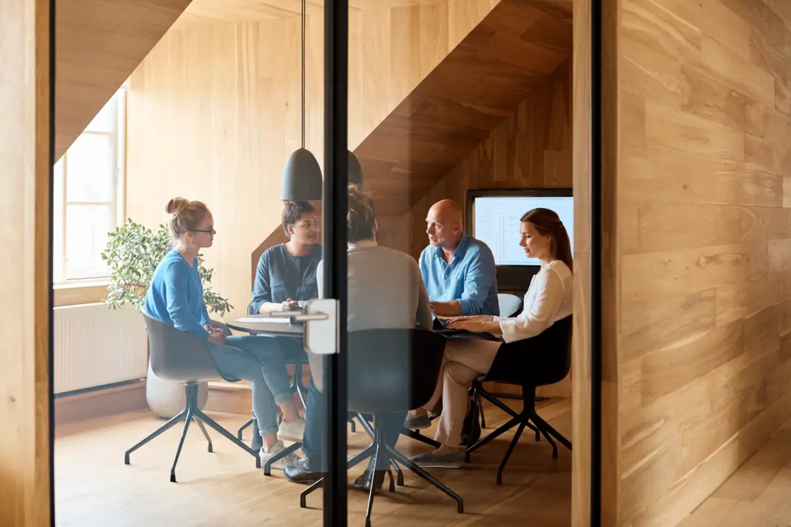 Business people discussing in meeting seen through glass door at office