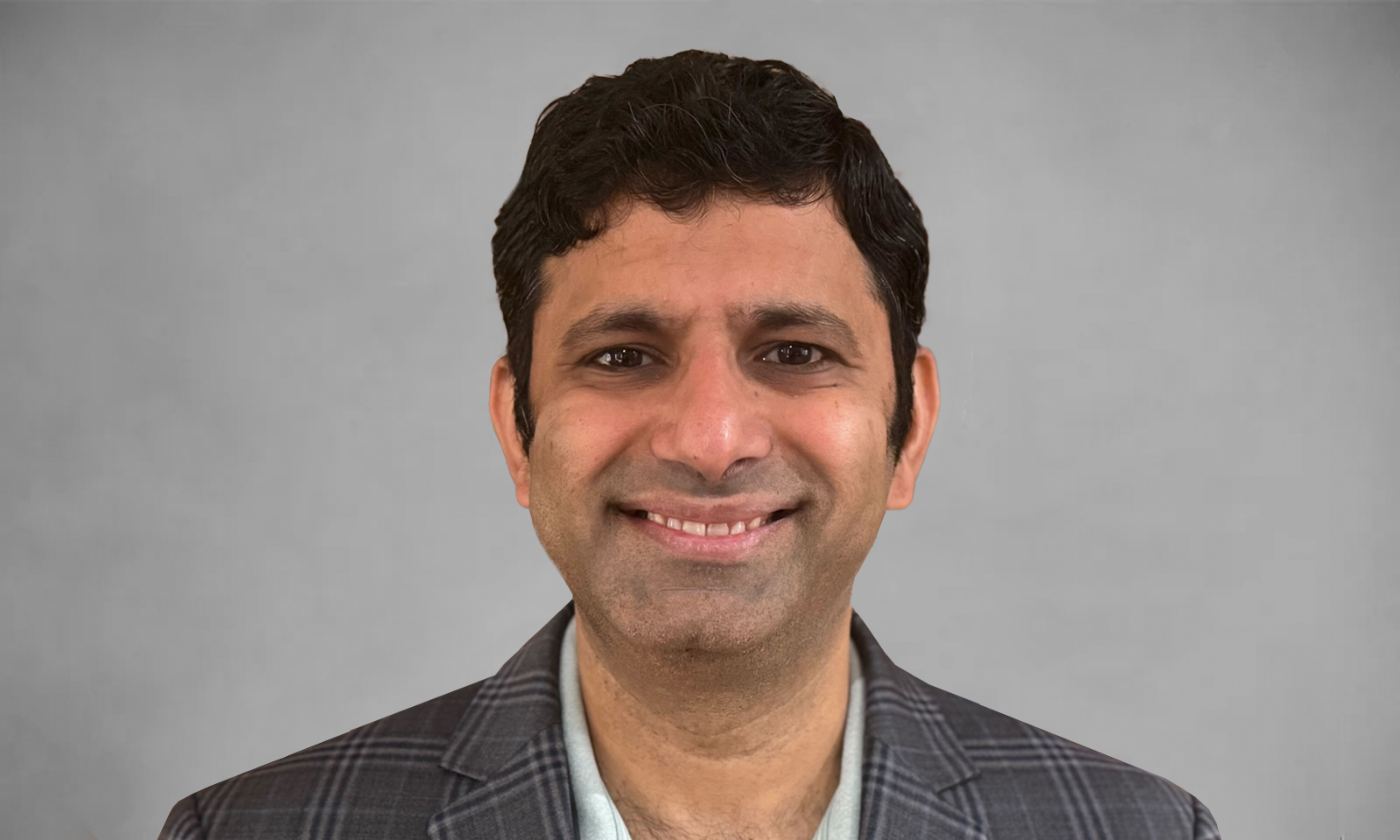 Gray rectangular card with Srini Venkatramani's headshot and white lines behind him