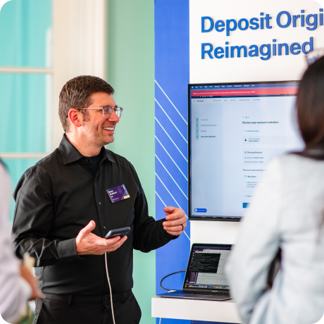 Man presenting Deposit accounts Reimagined to a woman at a kiosk