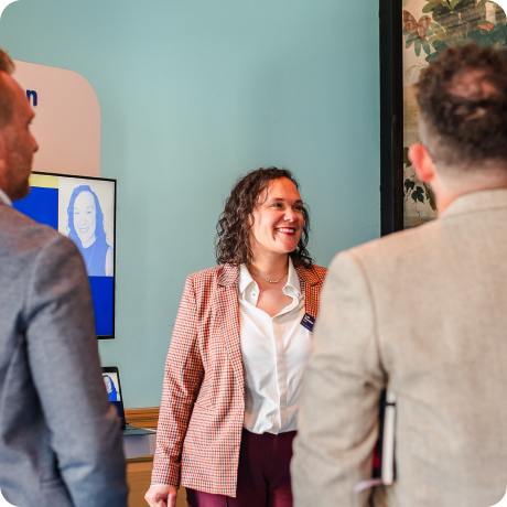 Woman standing in front of Kiosk, presenting to group of people