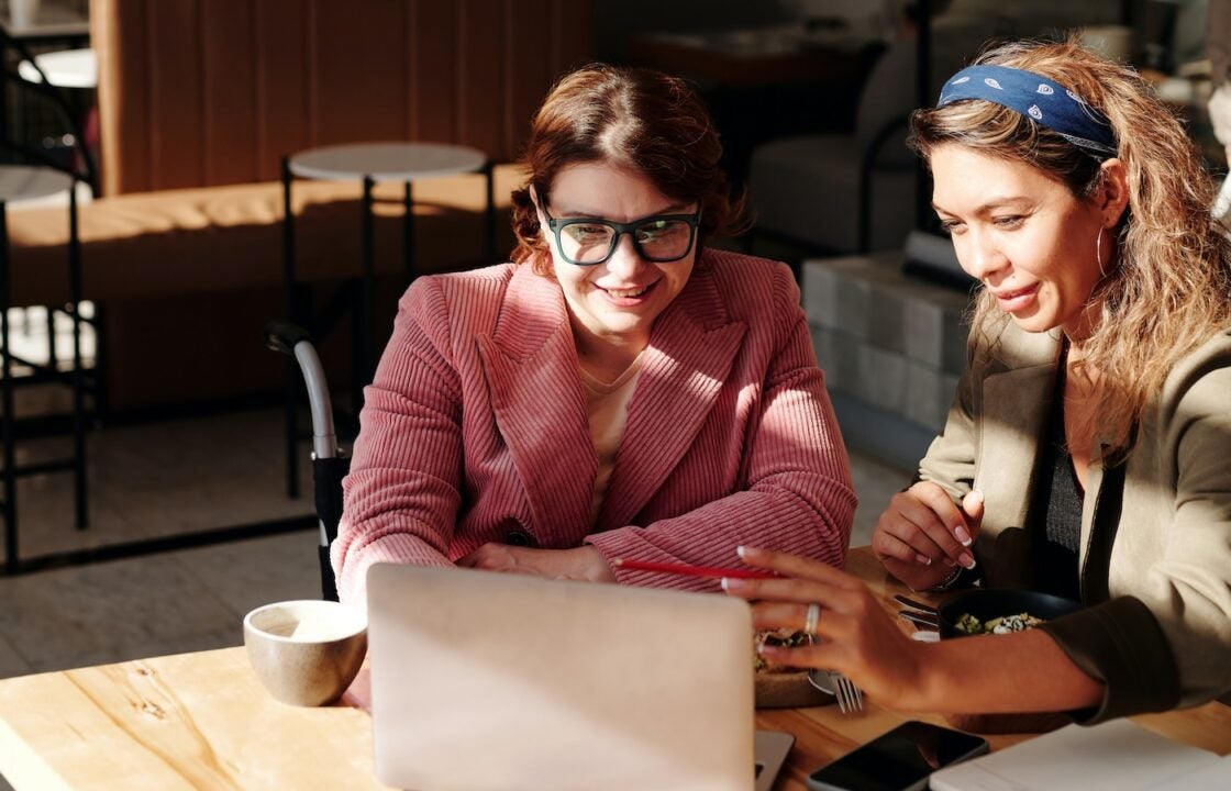 Two women looking at a laptop, discussing home equity solutions.
