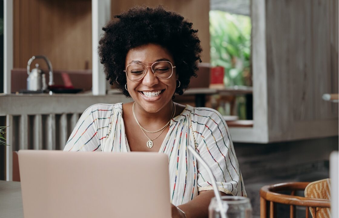 A smiling woman works on a laptop.