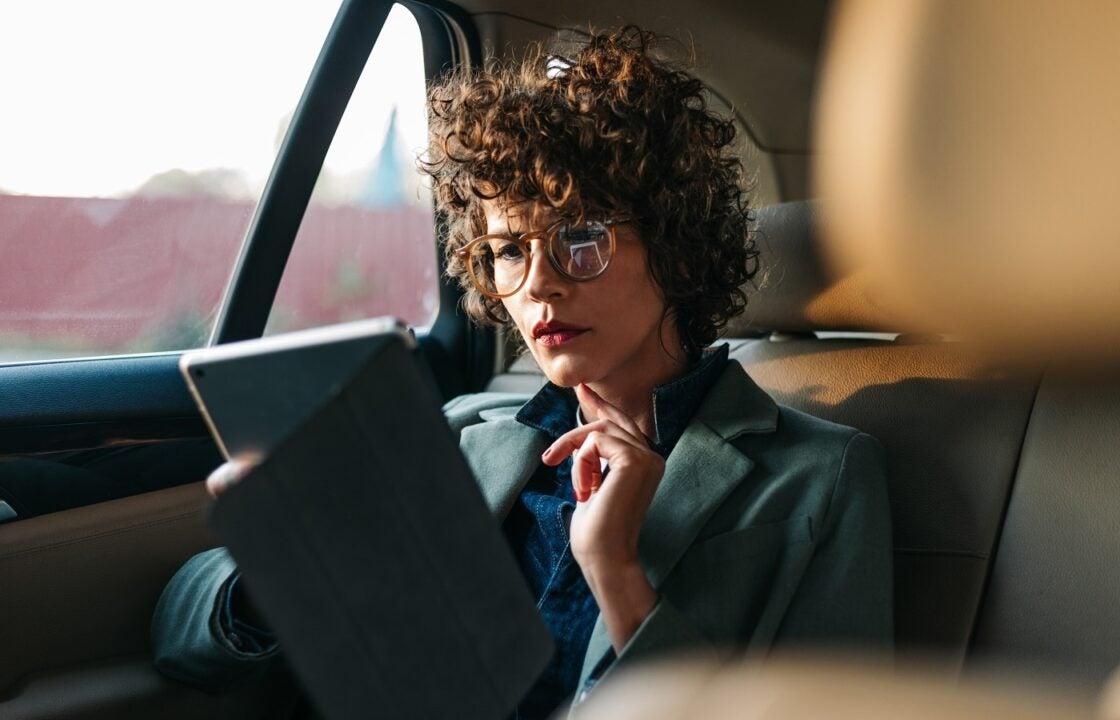Lender reviewing data on a tablet in the back of a car.